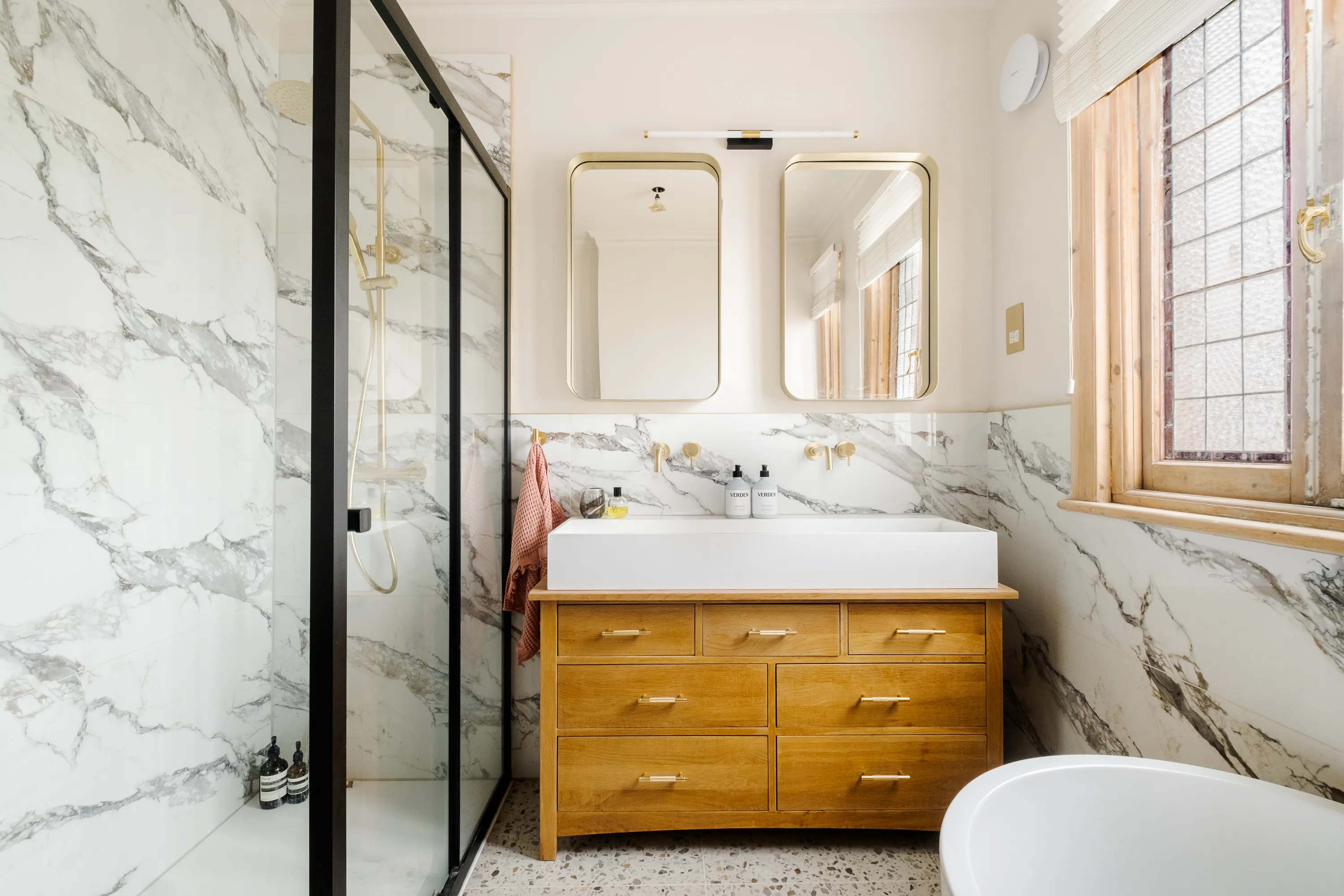 Photo of bathroom with marble walls and gold tap